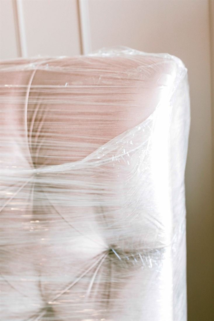Upholstered armchair shrink-wrapped for protection during furniture delivery